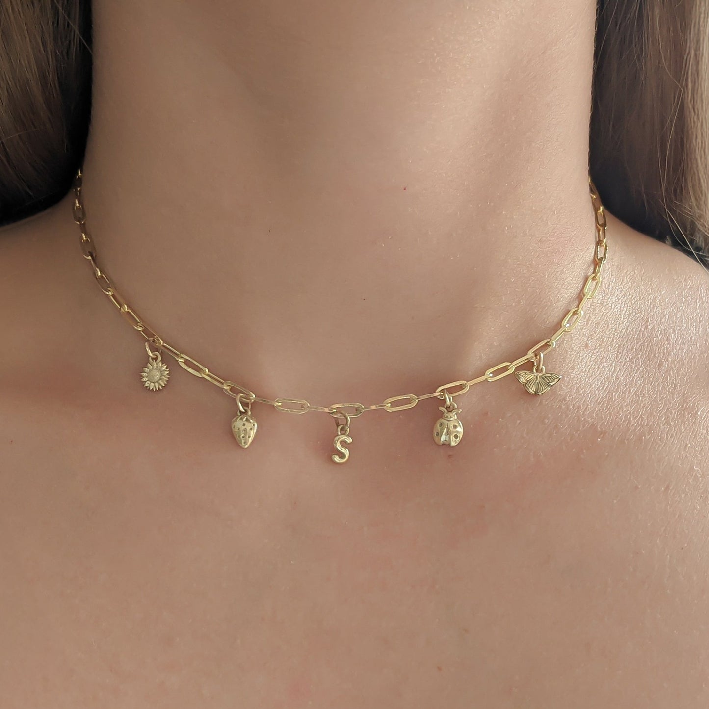 Gold necklace with small pendants on a person's neck